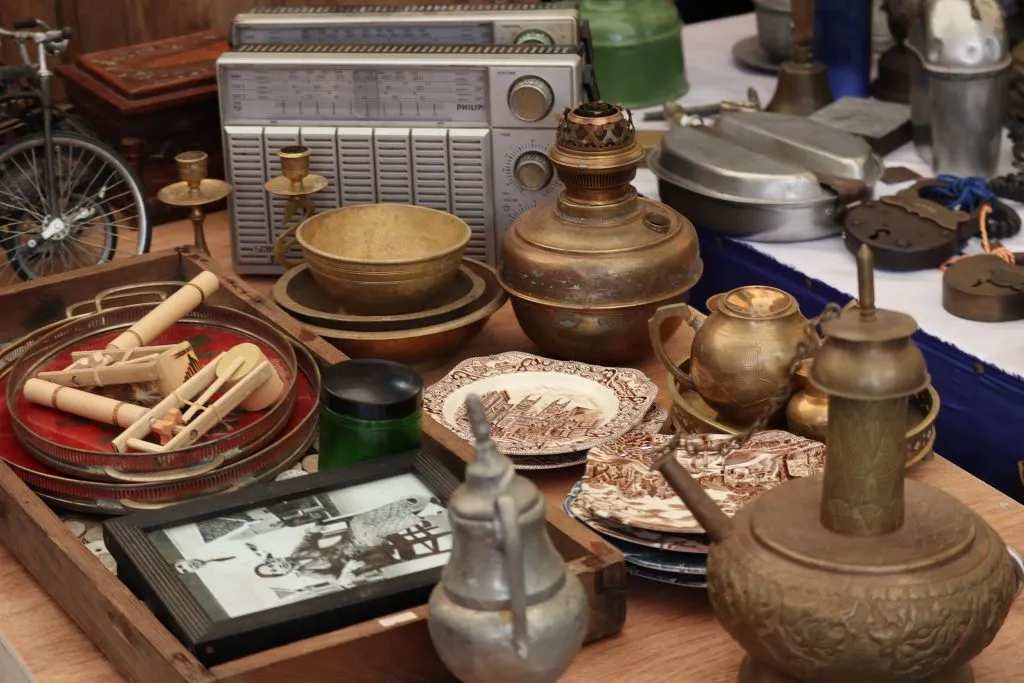 Brass radios, oil lamps, vintage plates, and other estate-sale antiques laid out for appraisal.